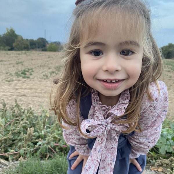 Petite Mauve: imagen de una niña pequeña al aire libre sonriendo a la cámara.